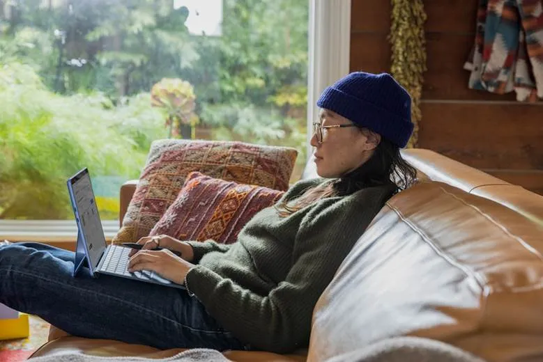A woman using her laptop to browse the net on how to implement proposal automation for her organization's benefit.